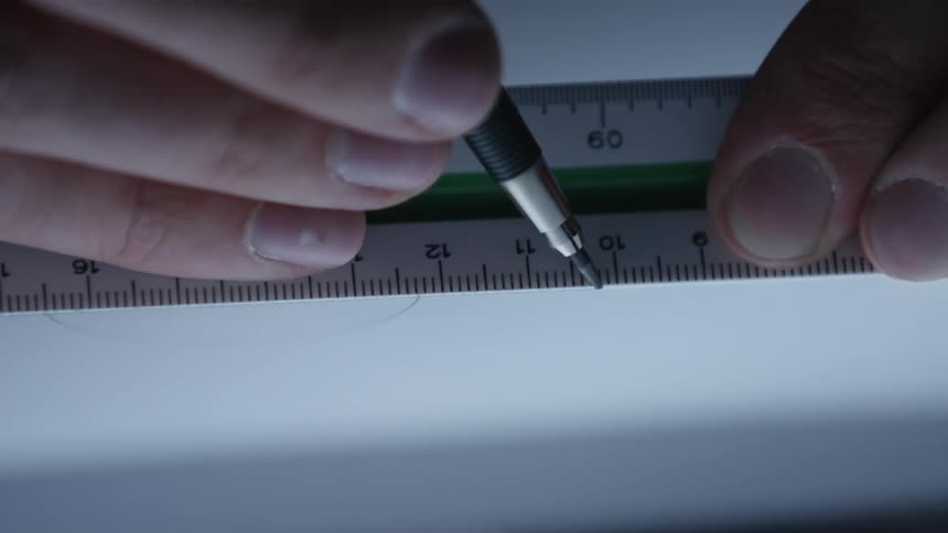 A close-up shot shows a hand drawing a straight line on paper with a pencil and a ruler on a lightbox