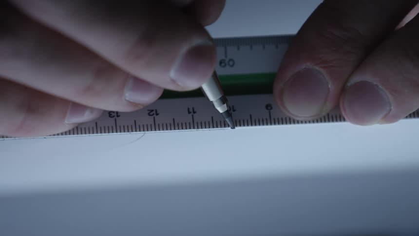 Close-up of a hand carefully drawing a straight line on paper with a ruler and mechanical pencil