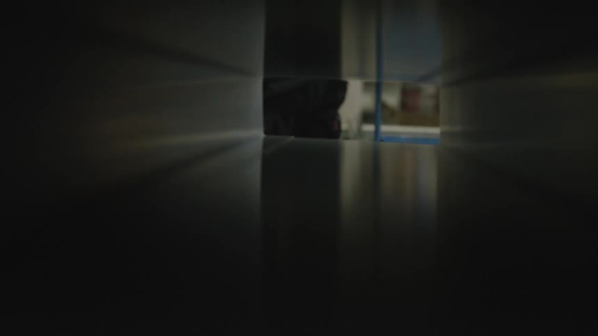 A unique point-of-view shot from inside a dark, reflective industrial tube as an object is slowly processed