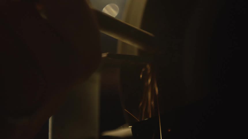 A close-up slow-motion shot of a metal tool being sharpened on a spinning grinder, sending a cascade of bright sparks through the dark workshop
