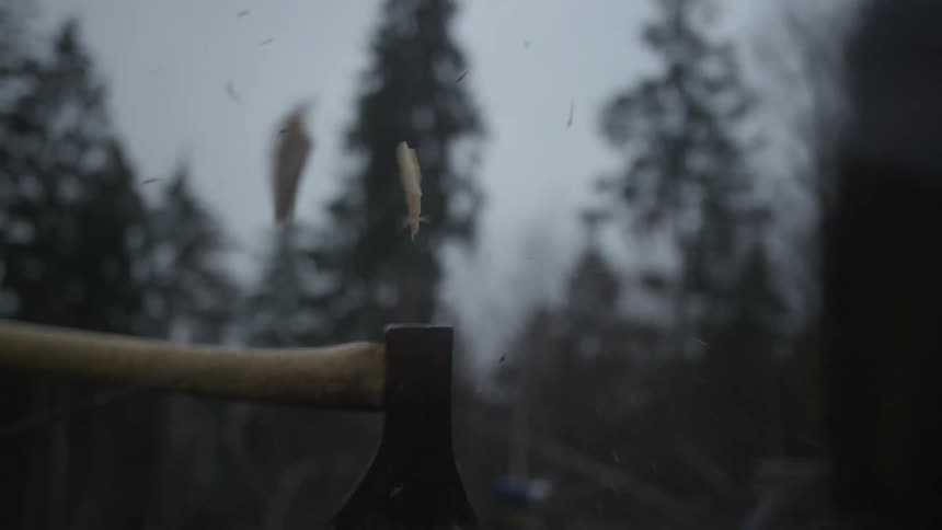 Dramatic super slow motion close up of an axe splitting a log in a dark and foggy forest