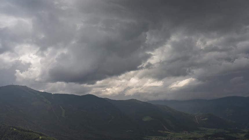 A dramatic time-lapse of dark, stormy clouds rolling over a vast mountain range