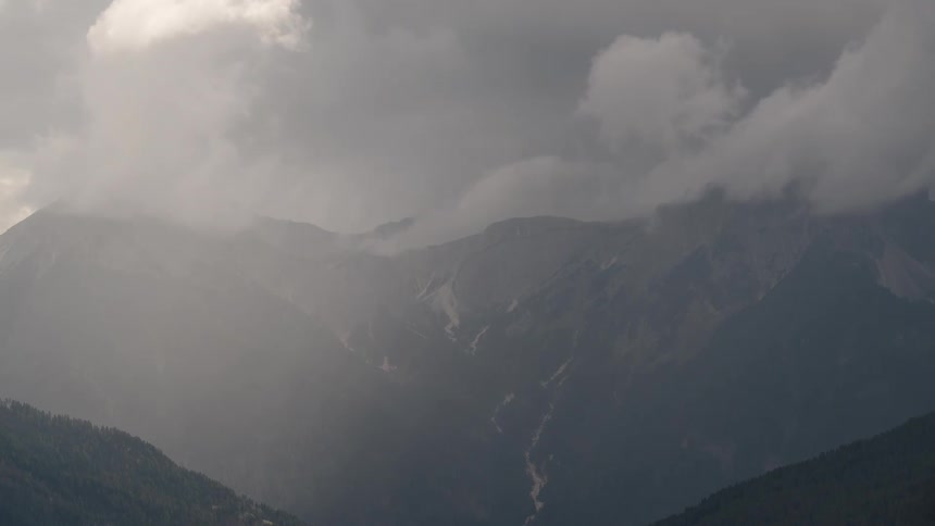 Dramatic clouds move across a hazy, sunlit mountain range