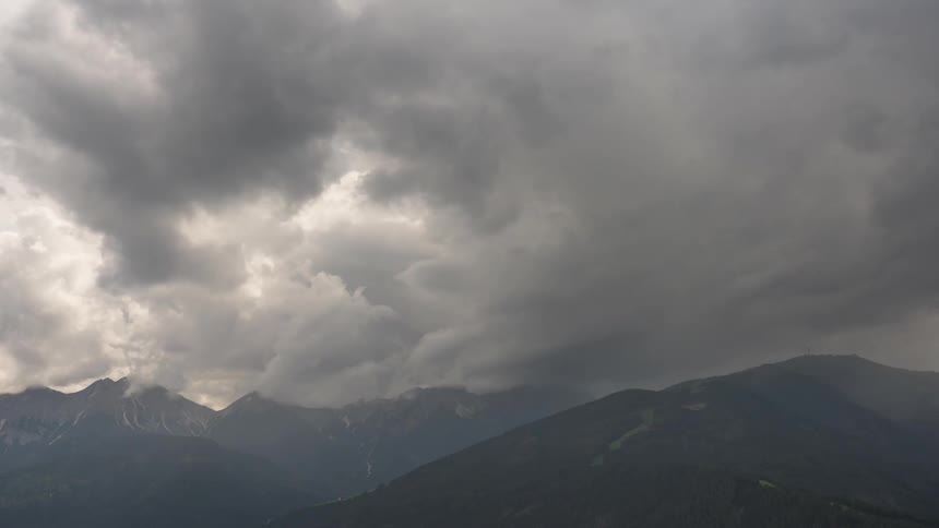 Dramatic time-lapse of dark, ominous storm clouds rolling in over a vast mountain range