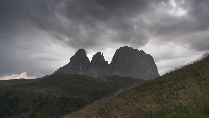 Dramatic storm clouds loom over the iconic Sassolungo mountain range in the Italian Dolomites