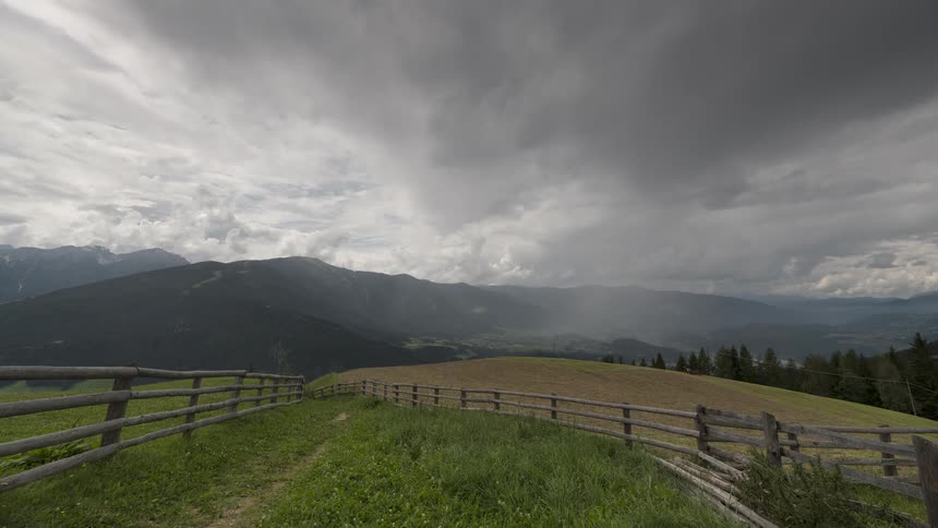 A dramatic time-lapse captures a powerful thunderstorm rolling over a lush green mountain valley