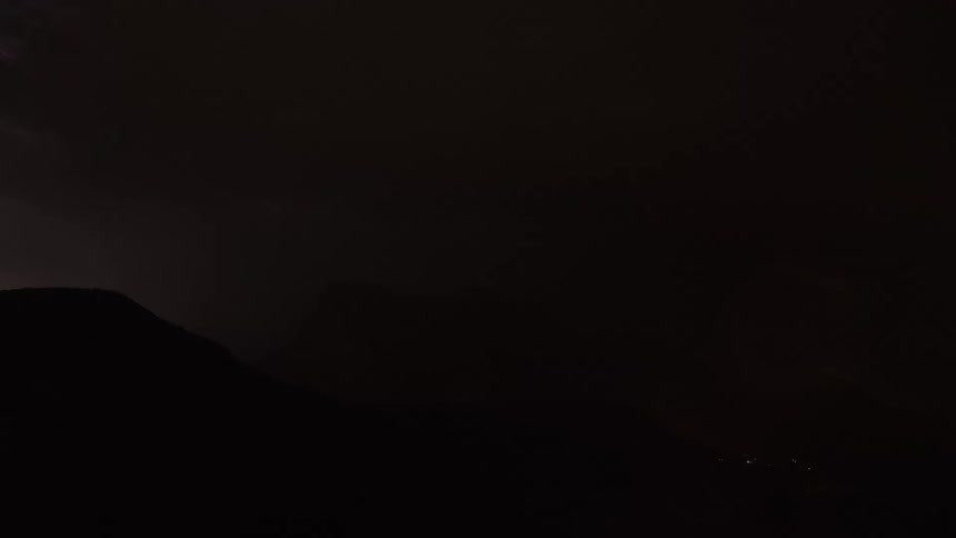 Dramatic flashes of lightning illuminate a dark and stormy mountain range at night