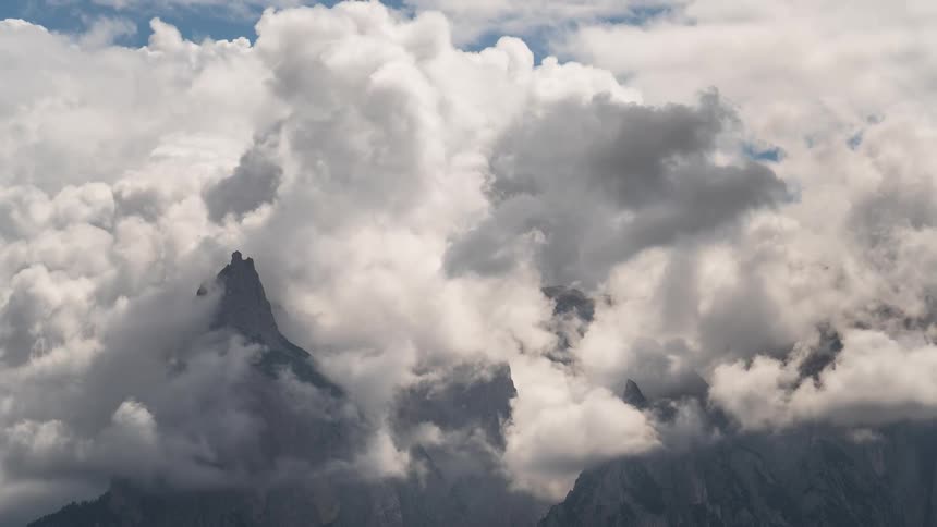 Dramatic timelapse of white and gray clouds swirling around and revealing majestic mountain peaks