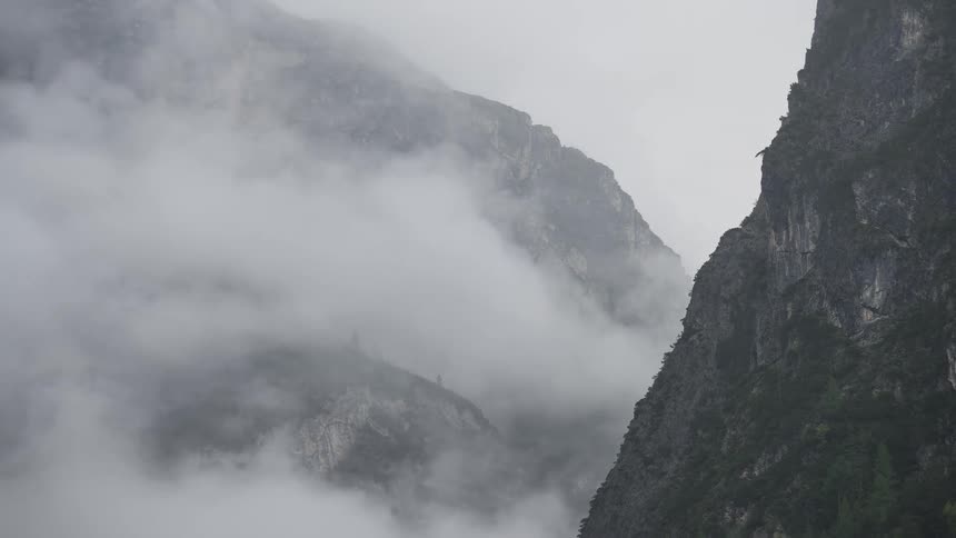 Dramatic timelapse of thick white clouds moving through a rugged mountain valley