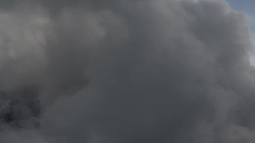 A dramatic timelapse shows thick, swirling clouds completely enveloping a rocky mountain peak