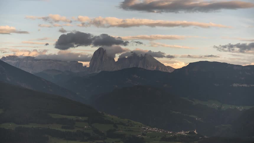 Time-lapse of clouds rolling over the majestic Dolomites mountain range during a tranquil sunset