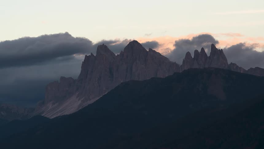 A stunning timelapse shows the last golden light of sunset fading on the dramatic peaks of the Dolomites as shadows rise and clouds gather