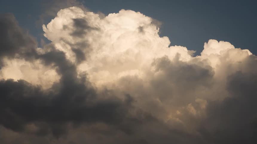 A dramatic time-lapse captures the churning and evolution of massive, stormy cumulus clouds against a deep blue sky