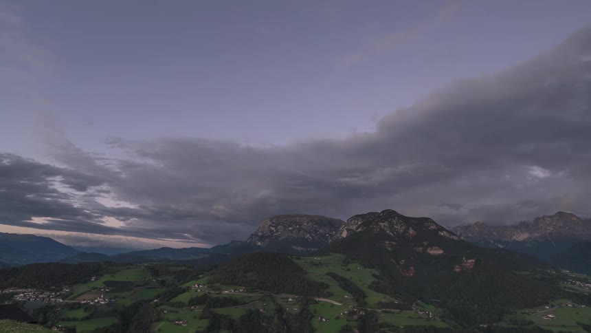 A stunning timelapse captures the transition from a vibrant sunset to twilight over a verdant mountain valley