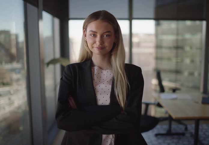Portrait of a confident blonde businesswoman standing with her arms crossed in a modern high-rise office