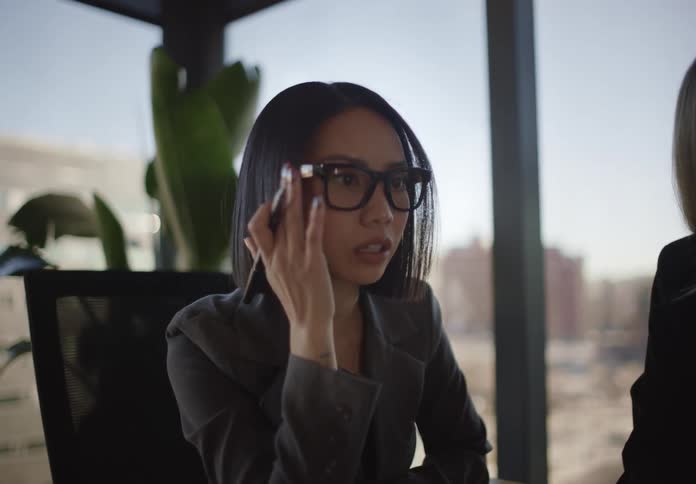 Side profile of a focused Asian businesswoman with glasses and a bob haircut participating in a meeting in a modern office