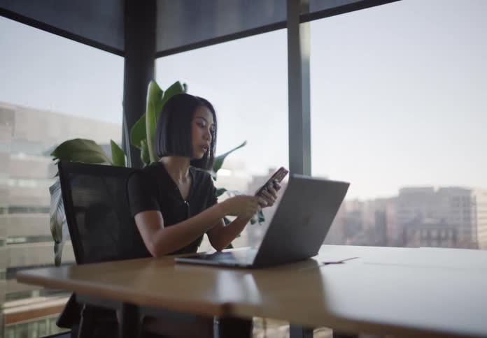 Stylish young businesswoman works on her laptop and makes an online purchase in a modern city office