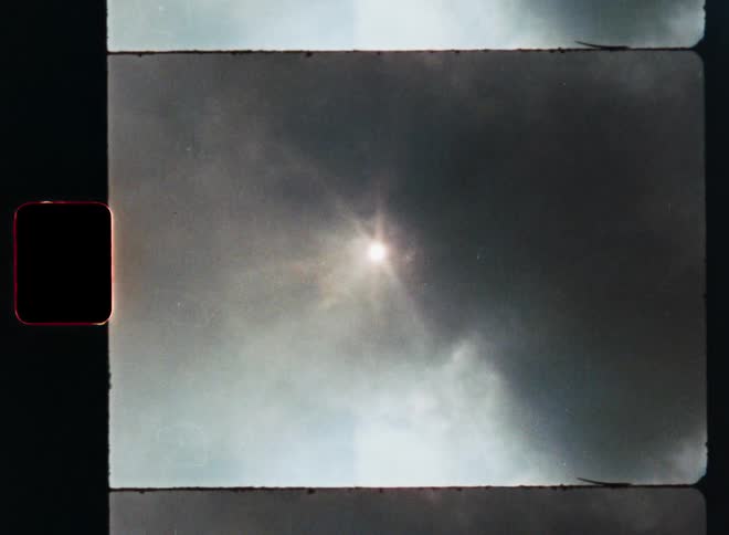 Vintage 8mm film scan shows a thick column of dark smoke rising and partially blocking the sun