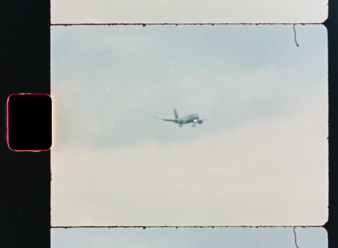 Vintage 8mm film scan shows a passenger airplane on its final approach to land