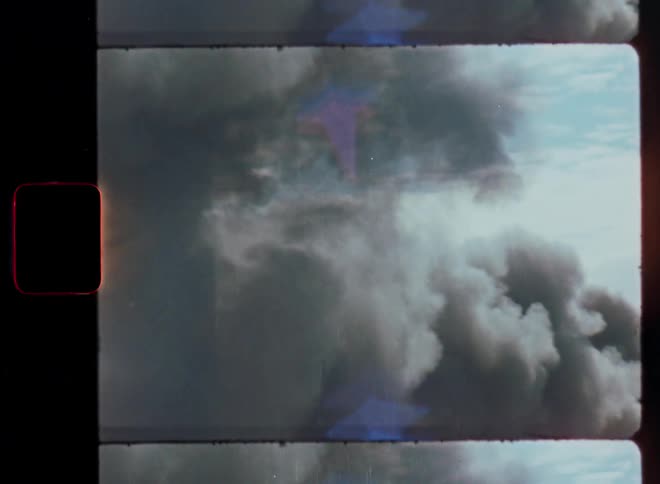 Vintage film strip footage of dark, ominous smoke billowing into the sky from a large fire