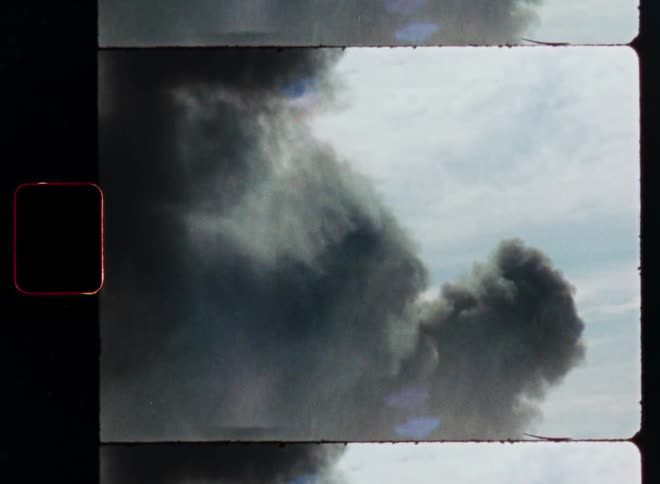 Archival film scan shows a massive plume of dark, thick smoke billowing into the sky