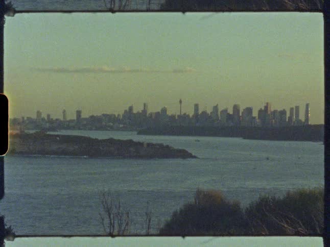 Super 16mm film scan of the distant Sydney, Australia city skyline over the harbor at dusk