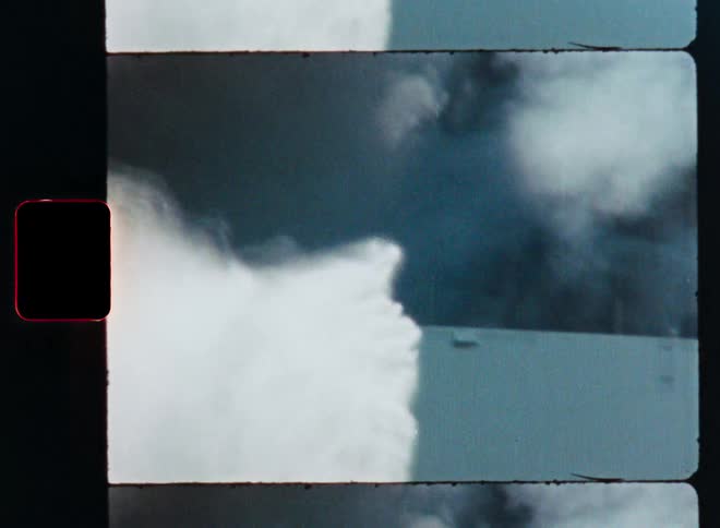 Vintage film footage shows firefighters spraying a powerful stream of water on a large building engulfed in thick smoke