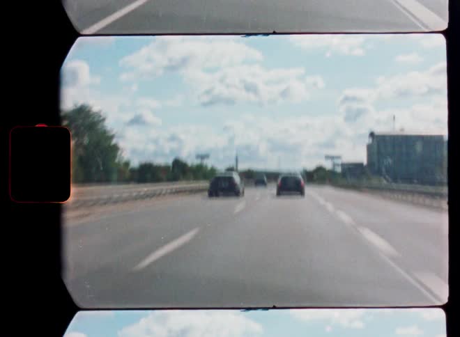 An analogue film captures a point-of-view drive along a busy highway on a sunny summer day