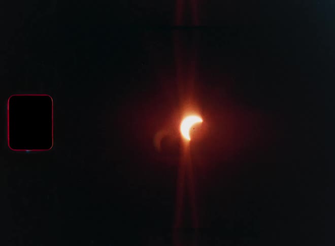 Vintage 8mm film footage of a partial solar eclipse with lens flare and film burn effects against a dark sky