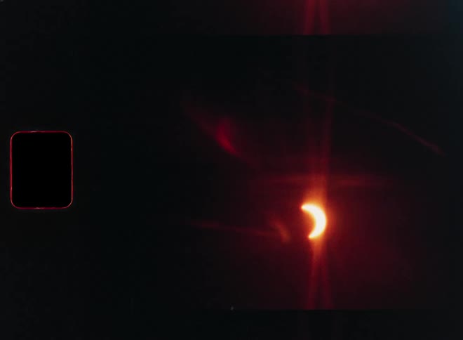 Vintage 8mm film captures a stunning time-lapse of a partial solar eclipse with prominent film grain and red lens flares