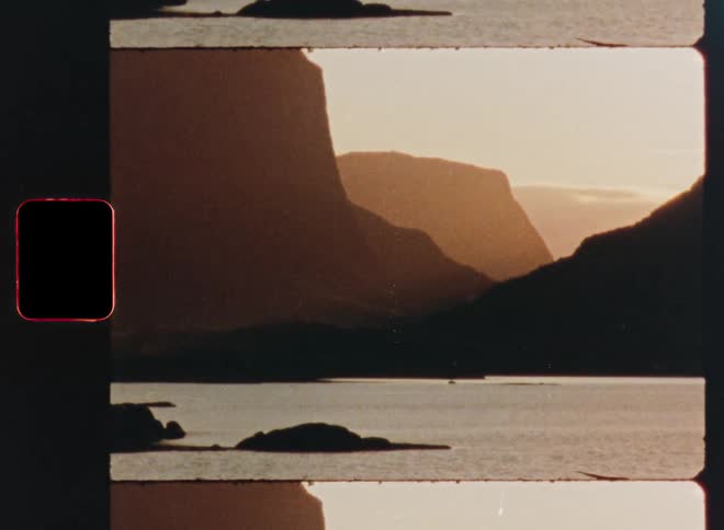 A scanned 8mm film strip reveals a scenic view of a majestic fjord surrounded by mountains during a warm sunset