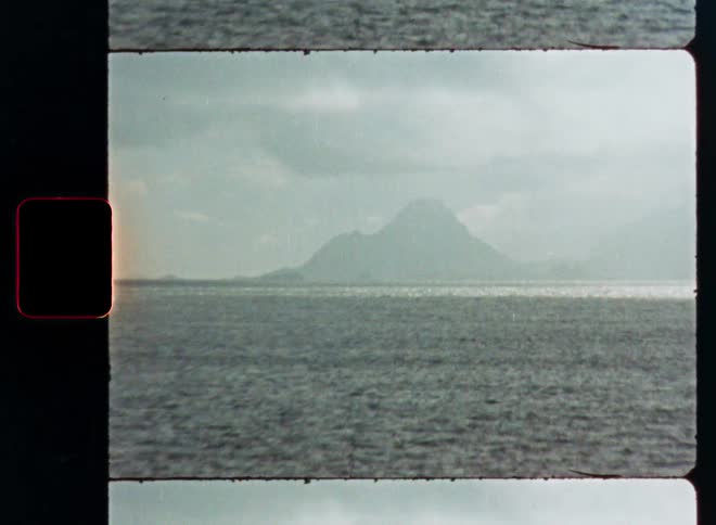 A vintage Super 8 film scans across the open sea, revealing a distant, hazy mountain on the horizon