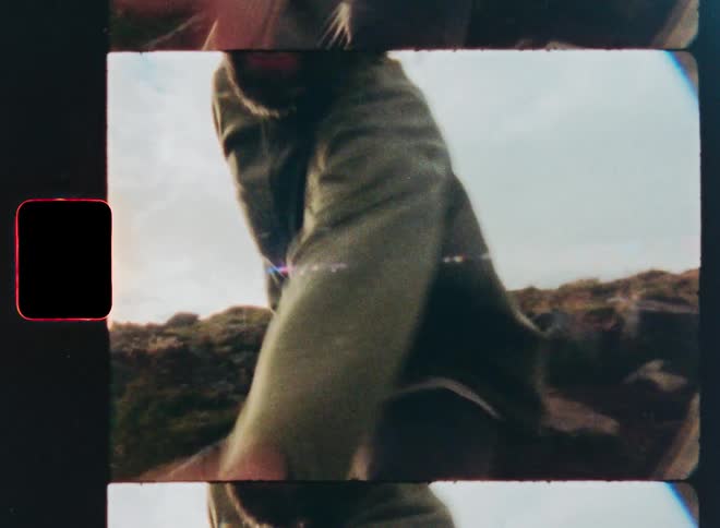 Point-of-view shot on vintage-style film of a smiling man reaching out his hand to lead the way on an outdoor adventure