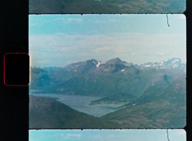 A nostalgic vintage film scan captures a serene view of a fjord nestled between vast, snow-dusted mountains