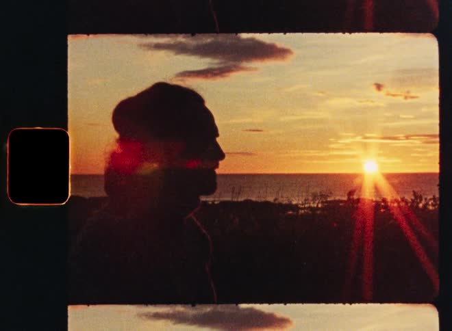 A vintage Super 8mm film captures the silhouette of a pensive woman watching the golden sun set over the ocean