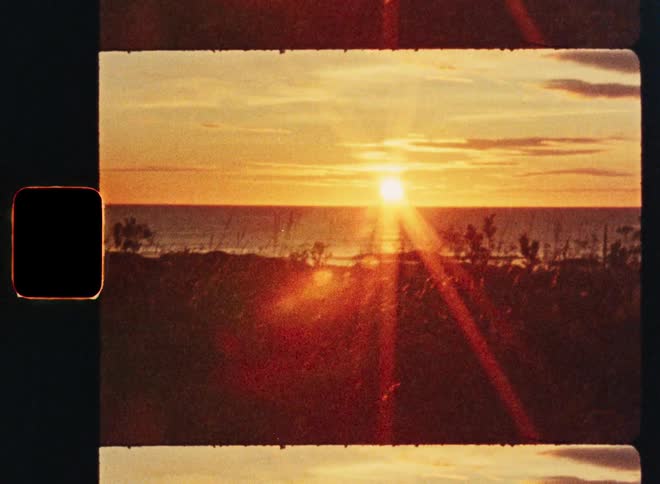 A beautiful golden sunset over the ocean with lens flare captured on vintage 8mm film