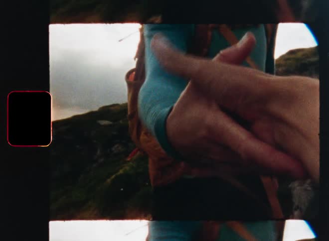 Vintage 8mm film footage shows a hiker reaching out their hand while trekking through a sun-drenched, mossy landscape