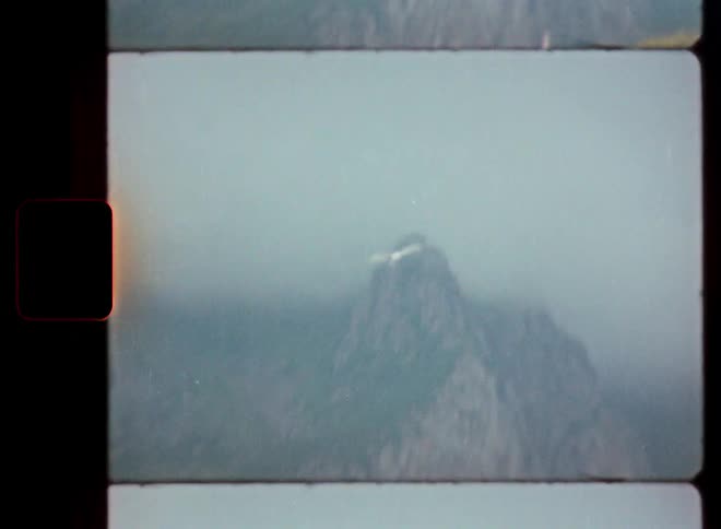 Vintage 8mm footage zooms from a coastal village in Norway to a lone seagull flying into the foggy mountains