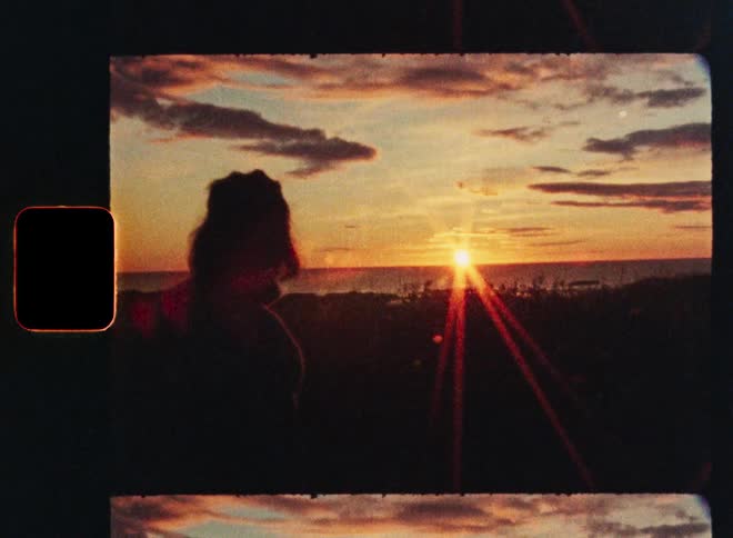 A vintage 8mm film shot starts on a person's silhouette and pans to a beautiful, colorful sunset over the ocean