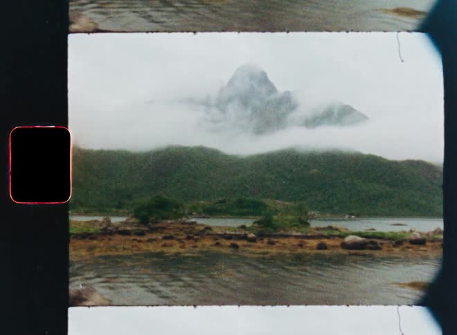 Vintage Super 8 film captures a moody pan across a tranquil fjord with a fog-shrouded mountain peak in the distance