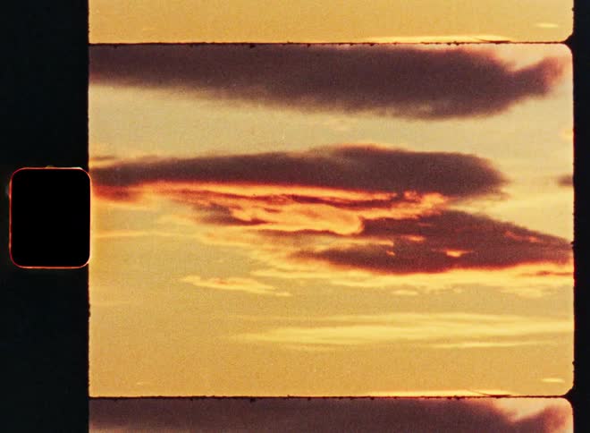 Vintage 8mm film scan of a serene golden hour sunset with red and orange-tinged clouds in the sky