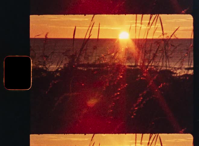 A beautiful golden hour sunset over the ocean is framed by tall beach grass on a vintage film strip