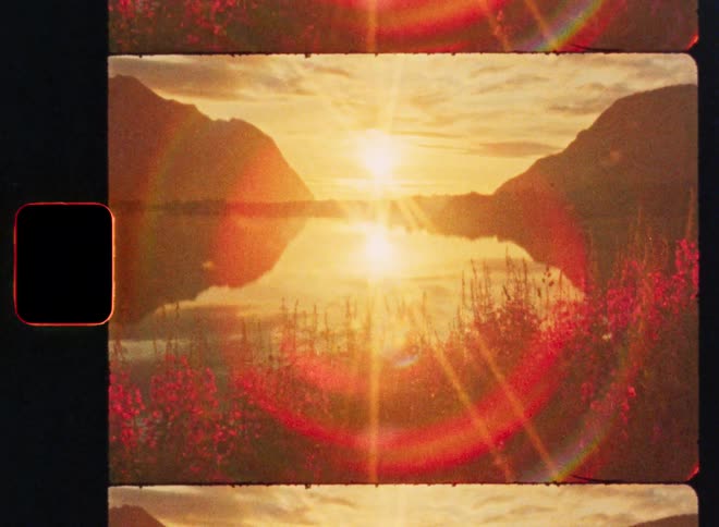 A dreamy, vintage 8mm film strip captures a golden sunset reflecting over a tranquil mountain lake with vibrant wildflowers in the foreground