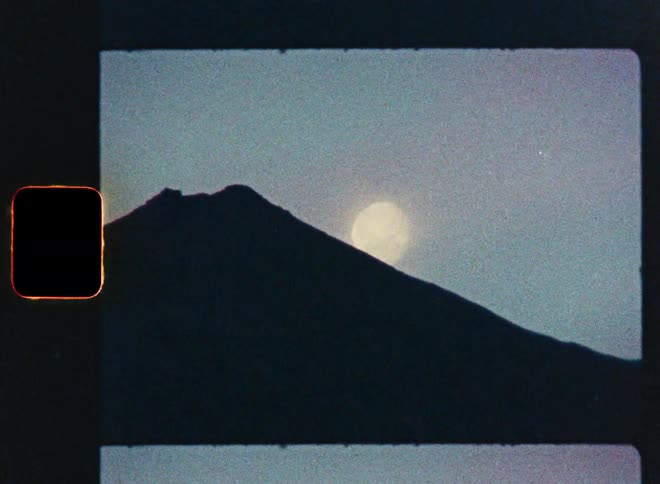 Archival 8mm film captures the sun setting behind the iconic silhouette of Mount Fuji in Japan