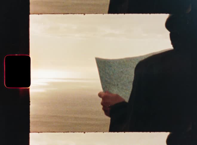 A person holds a map while overlooking a vast ocean and mountain landscape, captured in a vintage film strip style