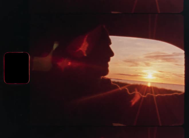A man drives a car along the coastline at sunset, with warm lens flare creating a nostalgic, vintage film aesthetic