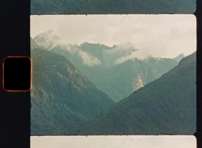 A vintage Super 8 film scan shows a beautiful, cloudy mountain valley in a stop-motion style