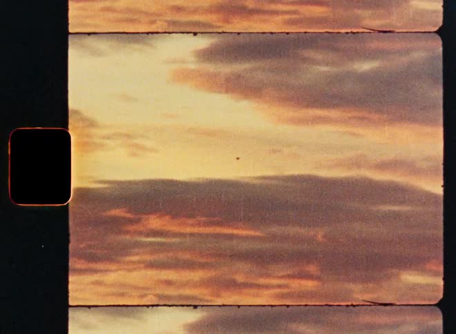 A vintage 8mm film scan of a dreamy, golden hour sunset with soft, colorful clouds passing by