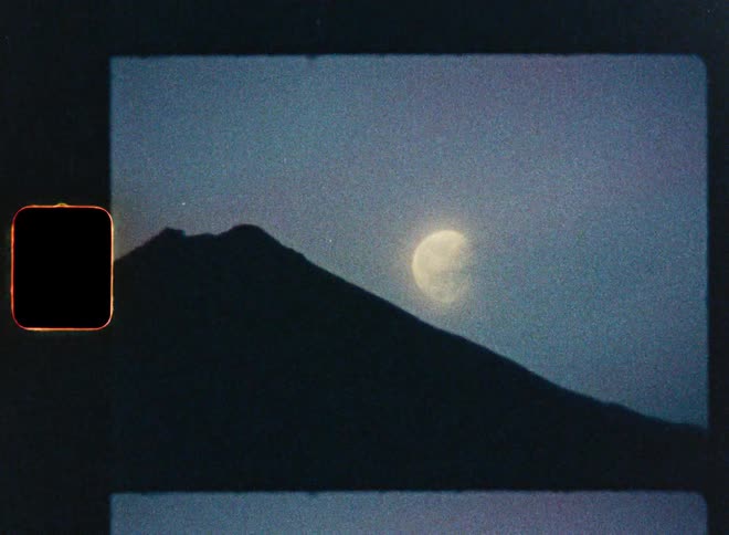 Vintage 8mm film scan captures a serene view of the moon rising beside a silhouetted mountain peak