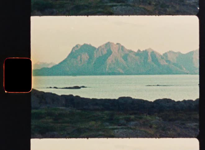 A super 8 film scan of a serene Scandinavian landscape with mountains across the water